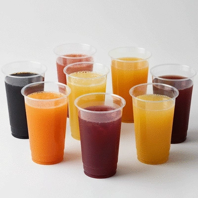 Variety of colorful plastic juice cups with different beverages, clean background